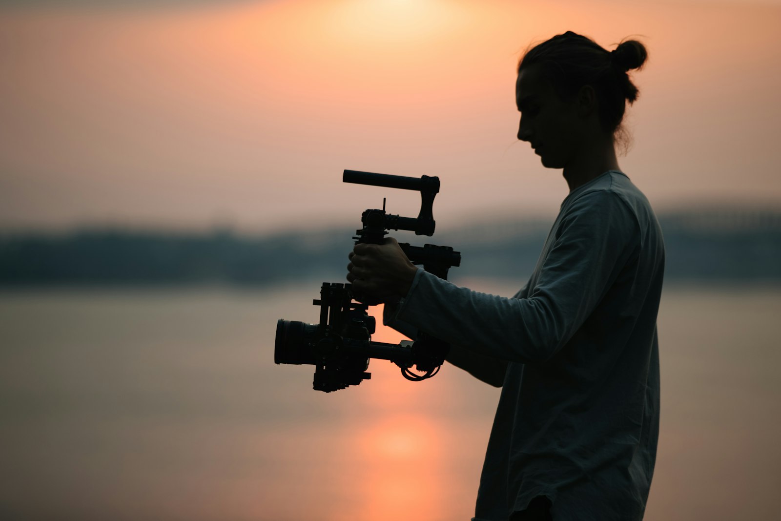 Cinematographer silhouette holding a camera at sunset