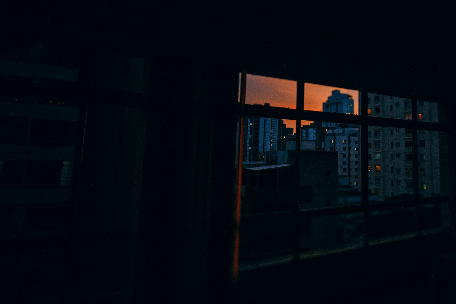 A city skyline through a window at dusk — the wider view